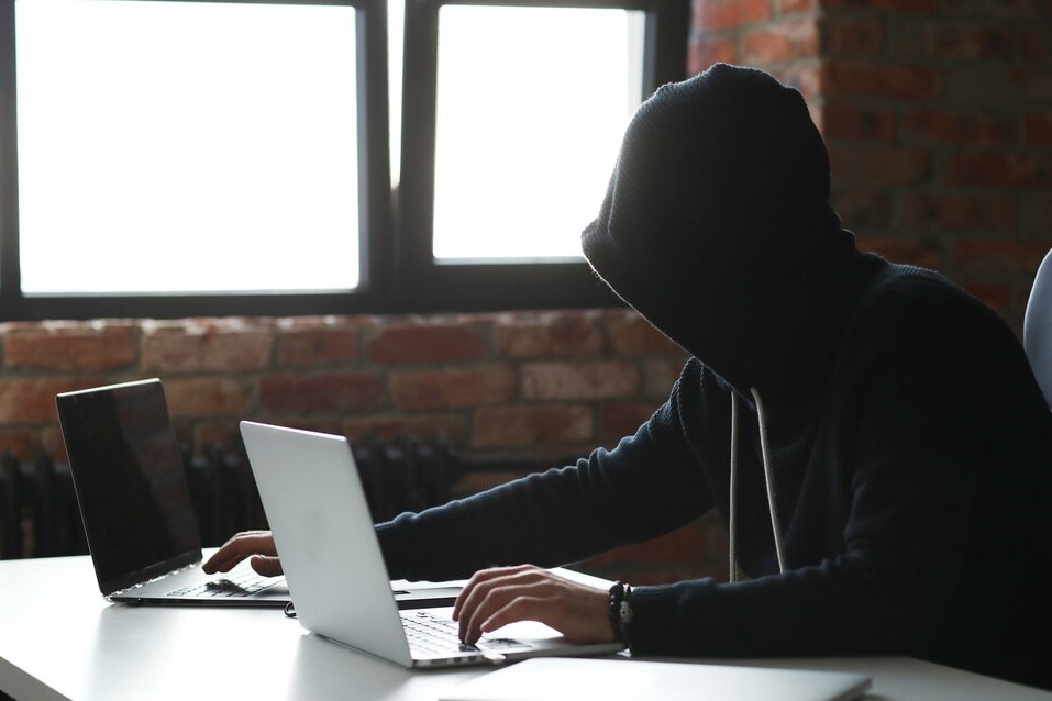 digital-identity-thief-in-front-of-two laptops-with-a-black-hoddie